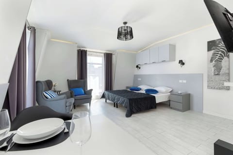 An open-concept living and sleeping area with two beds, a TV, and large windows that flood the space with light.

