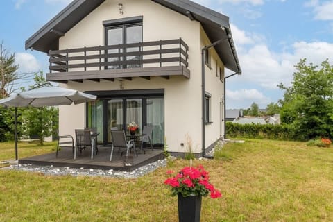 A beautiful house with a large yard, balcony, and lush greenery surrounding the property.

