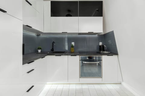 Fully equipped kitchenette with sleek white cabinetry and black backsplash.