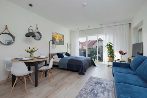 Bright studio with a seating area and a dining table, featuring a modern decor and large window for natural light.