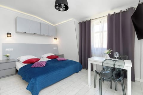 Bright and cozy studio apartment featuring a comfortable single beds, bedside lighting, and a modern interior design.