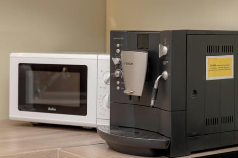 On the kitchen counter stand the coffee machine and microwave. 