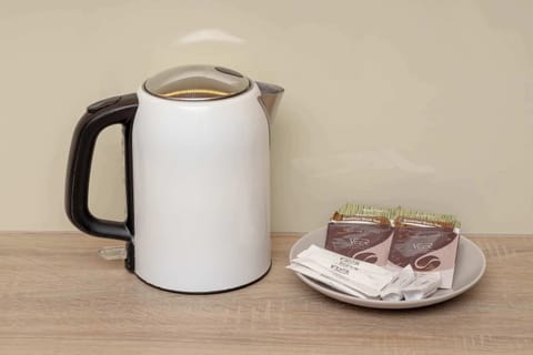 Electric kettle with tea and sugar beside it.
