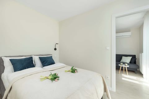 A cozy bedroom with a double bed, bedside tables, and natural light. The decor is simple yet elegant.