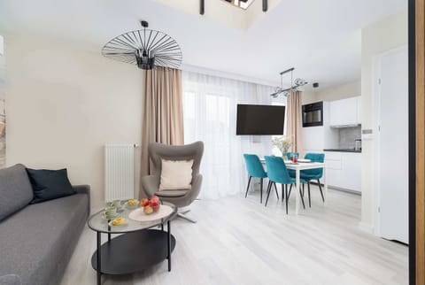 Spacious living room with a gray sofa, coffee table, armchair, television and kitchenette with dining area.