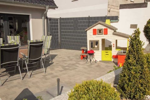 Große Terrasse mit Gartenmöbeln und Spielhaus für Kinder