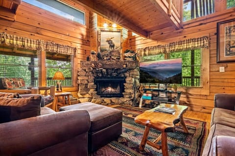 The centerpiece of the cabin, this inviting living room features a soaring stone fireplace, rich wood accents, and large windows that frame the forest outside. Perfect for gathering on cool mountain evenings.