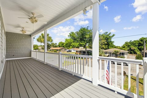 Spacious covered front porch with ceiling fans and sunny neighborhood views
