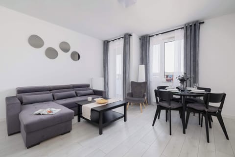Living room with a fold-out corner sofa, TV, access to balcony and dining area.