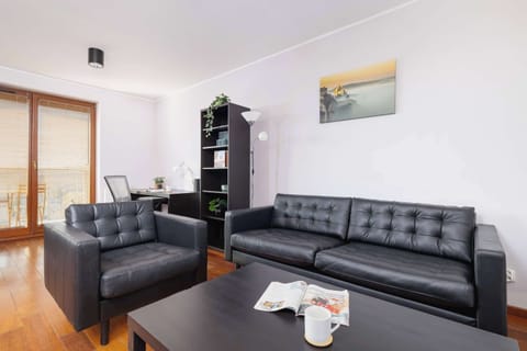 A cozy and elegant living room featuring black leather sofas, a small coffee table, and tasteful artwork on the wall.