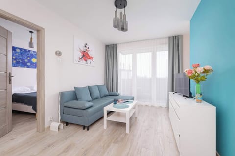 Stylish living room with bright blue double sofa bed, cable television and space for remote work.