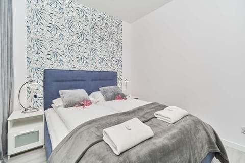 Bedroom with a blue and white color scheme, featuring a comfortable bed and patterned wallpaper for a cozy ambiance.