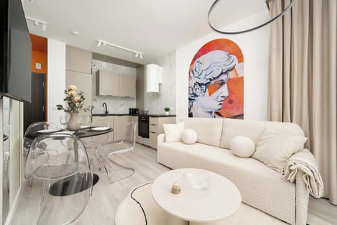 Modern living room with a round coffee table, a beige sofa and a kitchenette. 