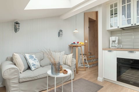 A cozy living room with a gray sofa and decorative cushions. A skylight brings in natural light, and a small coffee table sits nearby.
