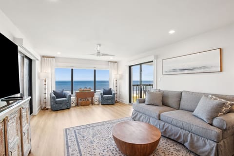 Relaxing Living Area Featuring Plush Couch and Chairs, a Flat Screen Smart TV, and Expansive Oceanfront Views