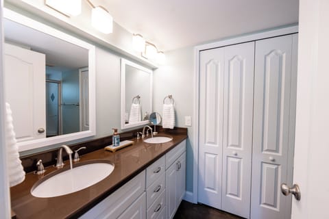 Spacious master bath with double vanity, bright lighting, and ample storage
