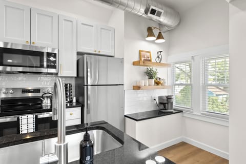 Sleek and modern kitchen with stainless steel appliances, open shelving, and plenty of natural light.