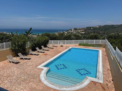 View from the balcony : swimming pool, olive groves and Agios Stefanos Beach