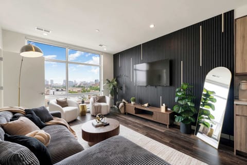 Sunlit modern living room w/ plush seating & sleek finishes, perfect for relaxing after a long day.