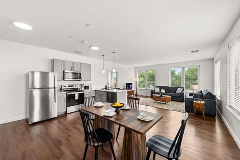 Spacious kitchen with island seating, dining table, and large windows bringing in natural light.