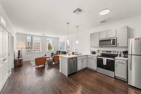 Open-concept kitchen and living area with stainless steel appliances, island seating, and comfortable furnishings.