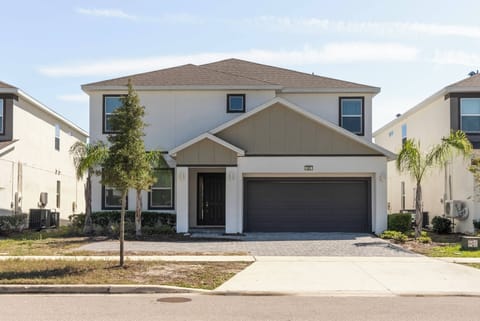 Experience a charming home with a warm entryway and tropical landscaping. The blend of light and dark tones creates an inviting atmosphere for your delightful stay in this thoughtfully designed space.