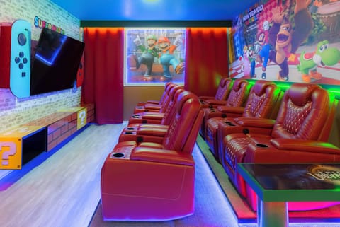 Welcome to our vibrant entertainment room, where plush red reclining seats ensure your comfort during movie nights. With a large screen and colorful decor, it's the perfect space for family fun and gaming adventures. Enjoy!