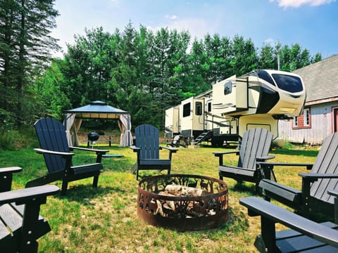 Home base — the 5th wheel set up on full hookups, trees lining two sides of the site.