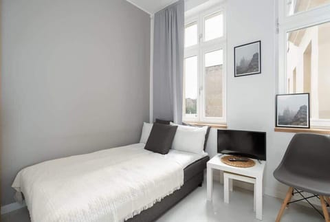 Bright room with a single bed, a small table, and modern furnishings, creating a cozy and functional space.

