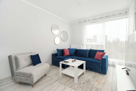 Bright and modern living room with two sofa beds, cable television, kitchenette, and dining area.
