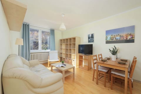 Living room with a sofa bed, TV, dining area and exit to balcony.