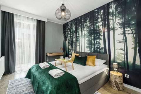 Bedroom featuring a green and white color palette, with a forest-themed accent wall and elegant decor.