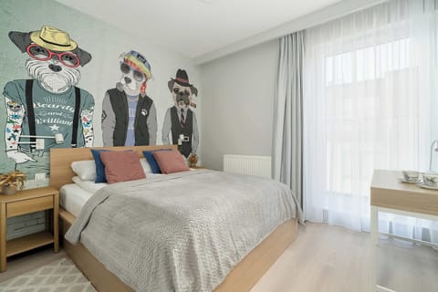 A modern bedroom with a large bed, stylish wall art and a bright atmosphere due to the large window with sheer curtains.