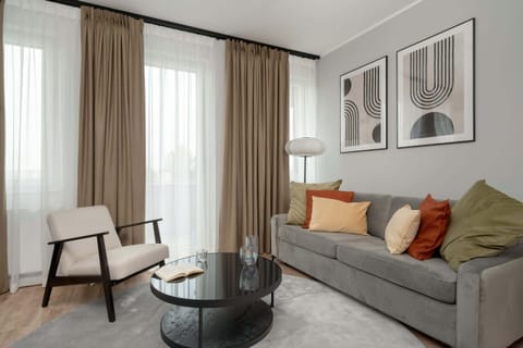 A plush sofa bed with colorful pillows and light curtains creating a welcoming space.