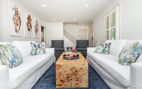 Cozy and stylish main relaxing area with rich Kentucky charm—features a curated bourbon display, horse racing artwork, and plush seating perfect for unwinding after a day at the track or distillery tour.
