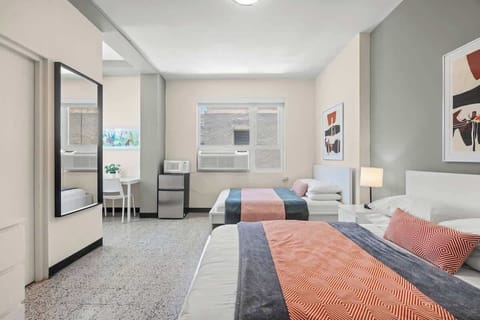 Discover comfort and space in this bright bedroom, featuring a plush bed and a full-length mirror, perfect for getting ready to explore the city or a last-minute check before heading out.