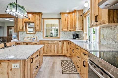 This beautiful kitchen boasts expansive counter space, rich wood cabinets, modern lighting, and scenic views, perfect for any cooking enthusiast.