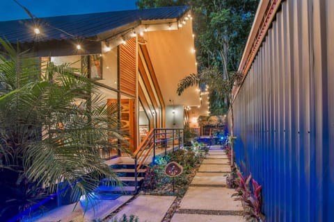 Modern tropical home exterior illuminated at night, featuring warm lighting, lush, Aloki Wim 4 in Playa Chiquita