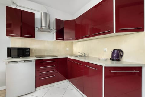 Fully equipped kitchenette with red modern cabinets.