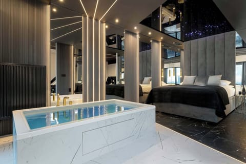 A sleek white hydromassage tub with a marble backdrop and golden accents, adding a touch of sophistication.