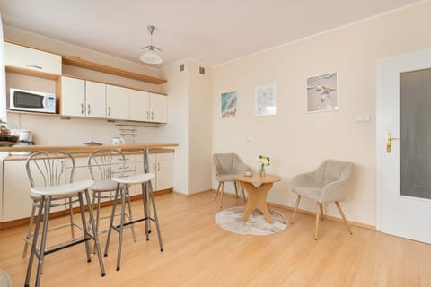 A modern kitchenette with a table, high bar stools, and light-colored cabinets offers a convenient space for meal preparation.