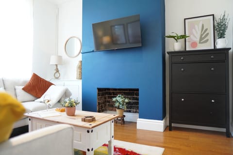 Stylish living room with blue feature wall, TV, fireplace and cosy seating.