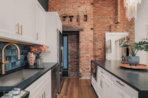 The modern kitchen is fully stocked with everything you need and thoughtfully blends contemporary design with historic charm, featuring the original exposed brick.