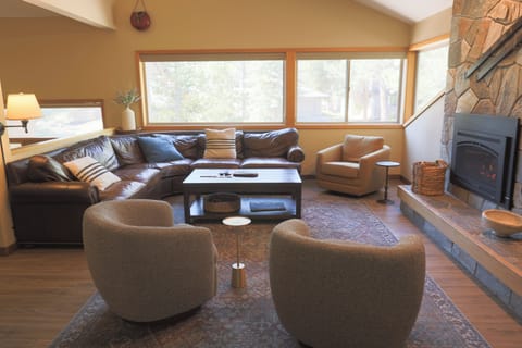 Sink into plush seating and let the warmth of the stone fireplace embrace you while natural light floods this inviting living room—your peaceful mountain retreat awaits.