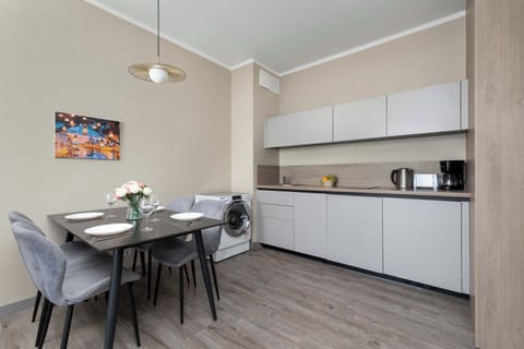 A modern kitchenette with glossy white cabinets, a contrasting dark countertop, and built-in appliances looks both functional and stylish.