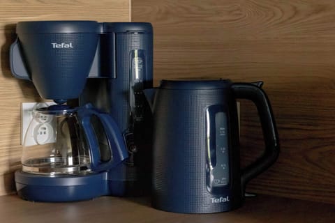 A kitchen corner showcasing a coffee set including a drip coffee maker, electric kettle, and toaster in navy blue.