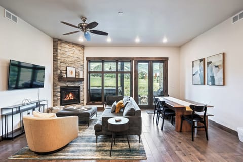 - Gather in the open living area with fireplace and TV  
- Large windows showcase mountain scenery and greenery  
- Dining and lounge spaces flow together for easy living