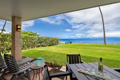 Ground-floor oceanfront lanai with seating and sweeping blue water views.