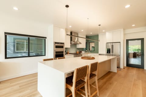 Kitchen: fully equipped with stainless steel appliances, a gas range, stone countertops, modern lighting, and a large island with seating for 4