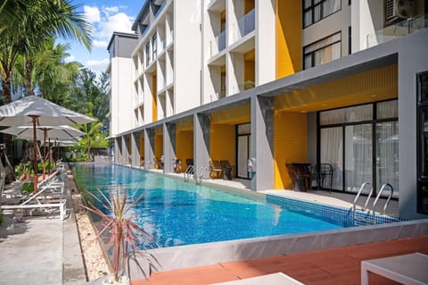 Outdoor pool with sun loungers and modern building facade perfect for relaxing afternoons.